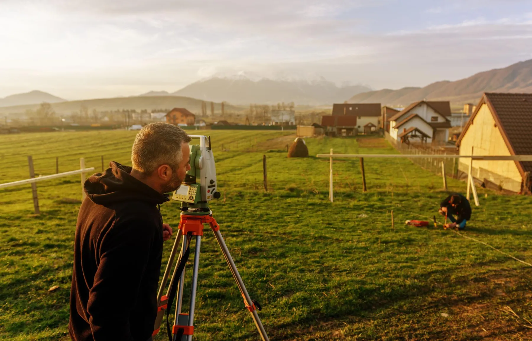 Surveyor sighting through a tripod in the field